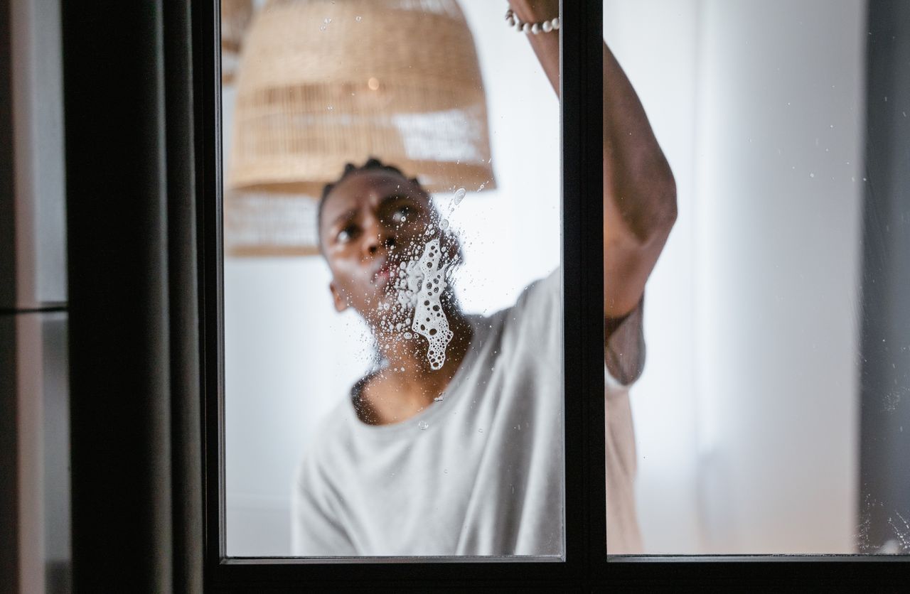 services-02 An adult man cleaning an indoor glass window, centered on household chores and keeping things clean.